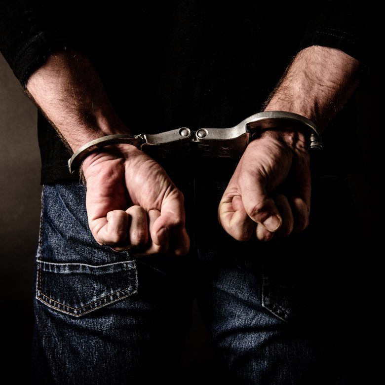 Arrested suspect with handcuffs behind his body.